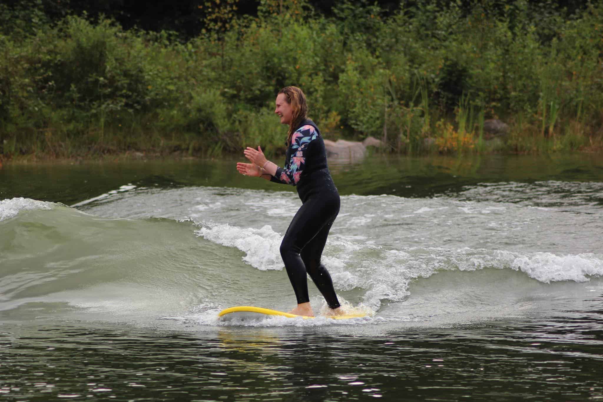 lady on surfboard in water clapping hands